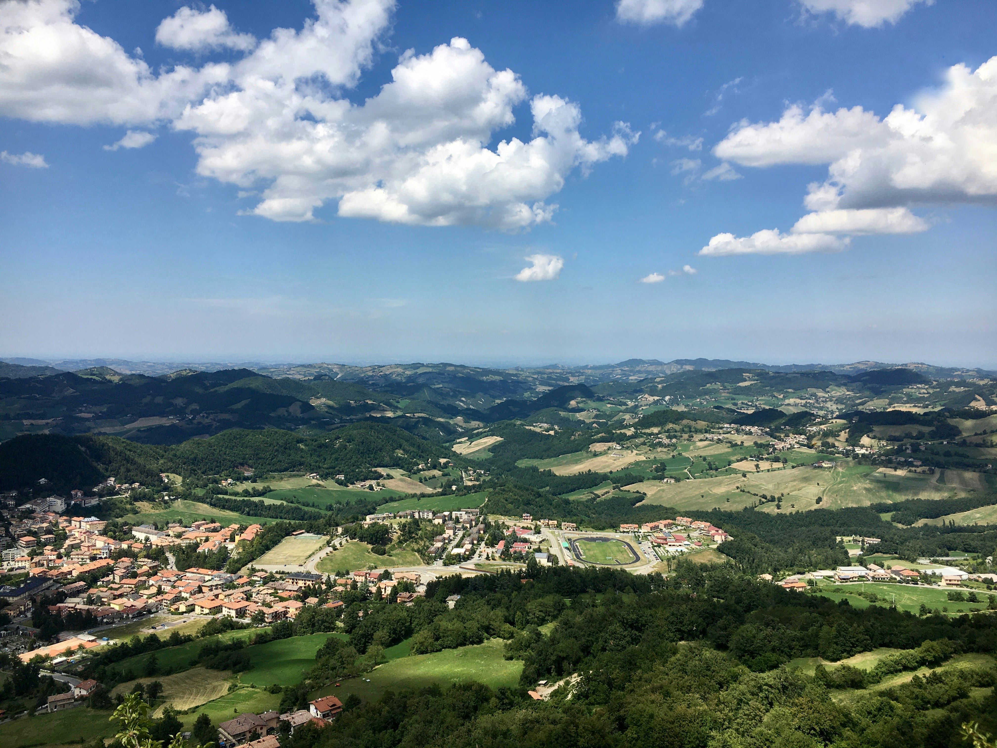 green trees and houses under blue sky and white clouds during daytime